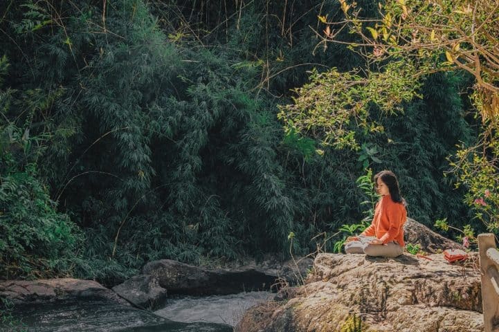 woman sitting in nature practicing yoga for addiction recovery
